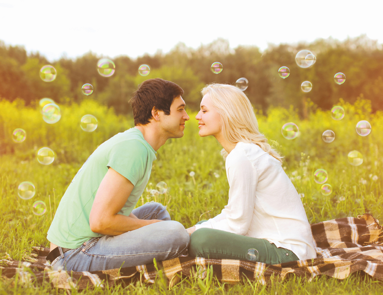 Pretty romantic couple in love having fun soap bubbles