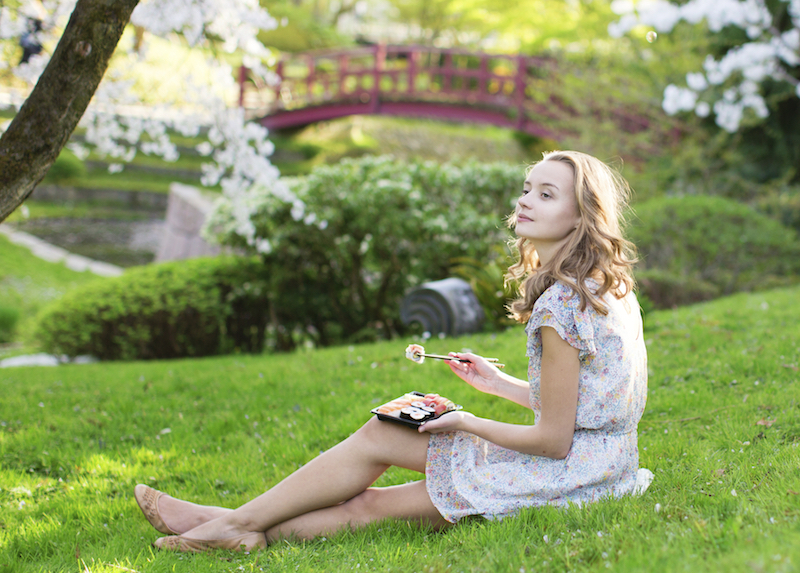 Young European woman eating sushi in Japanese park