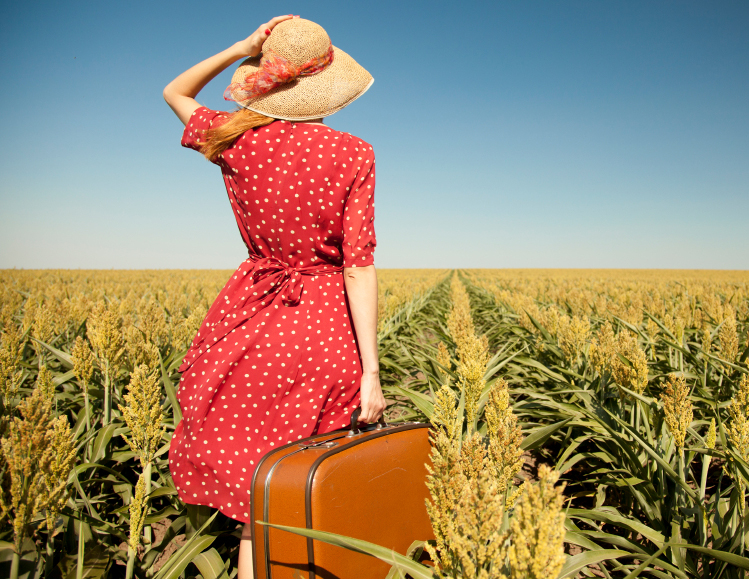 Redhead girl with suitcase at corn field.