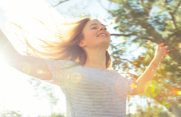 Joyful woman leaning out of a car sunroof