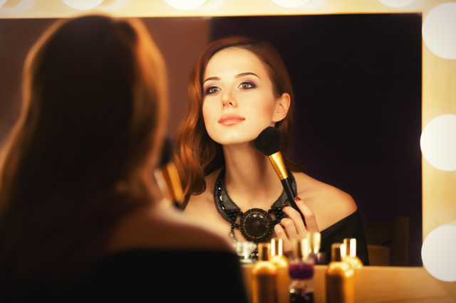 Beautiful redhead women appling makeup near mirror