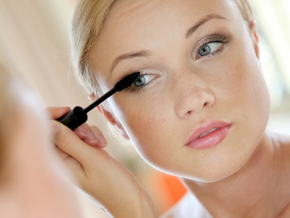 Portrait of young woman putting mascara on