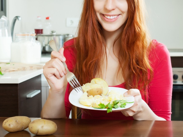 positive girl in red eating jacket potatoes