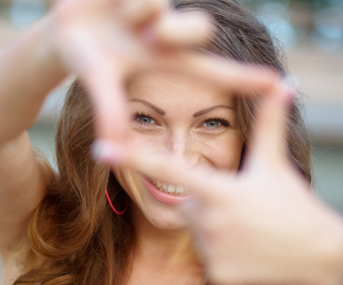 Closeup of young beautiful woman making frame with her hands